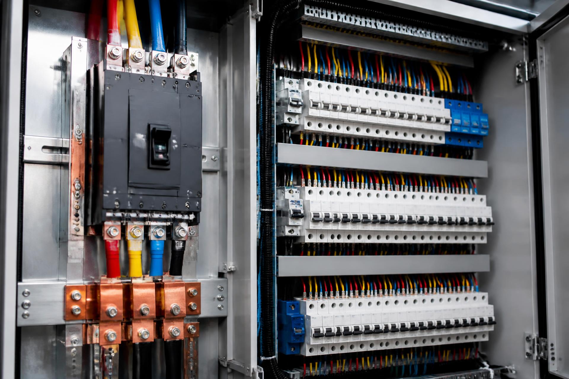 Heavy-duty commercial main switchboard with organized rows of circuit breakers, copper busbars and multi-color industrial three-phase cables